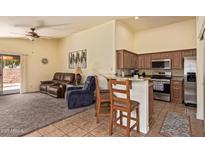 Open concept living room with a kitchen, tile floors, ceiling fan and comfortable seating at 16274 N 138Th Ln, Surprise, AZ 85374