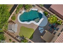 Aerial view of a backyard oasis featuring a freeform pool, lush landscaping, and comfortable seating area at 20426 N Alma Dr, Maricopa, AZ 85138