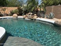 Inviting pool with rock waterfall feature and lush landscaping, perfect for relaxing and entertaining outdoors at 20426 N Alma Dr, Maricopa, AZ 85138