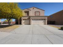 Tan two-story home featuring a spacious three-car garage and a mature tree in the front yard at 23104 W Kimberly Dr, Buckeye, AZ 85326