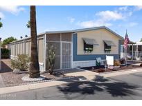 Charming manufactured home featuring a well-maintained yard, covered entry, and classic American flag at 535 S Alma School Rd # 85, Mesa, AZ 85210