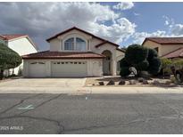 Charming two-story home with a three-car garage, arched entry, well-maintained landscaping, and a red tile roof at 11403 W Rosewood Dr, Avondale, AZ 85392
