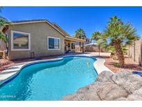 Inviting pool area with palm trees and rock features, perfect for outdoor relaxation and entertaining at 43302 W Bunker Dr, Maricopa, AZ 85138