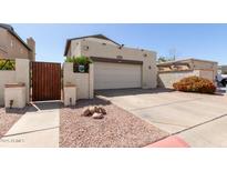 View of the home's driveway and the attached two-car garage with a decorative wooden gate at 630 E Jensen St # 116, Mesa, AZ 85203