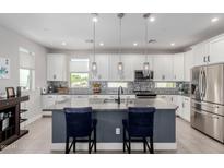 Modern kitchen featuring white cabinets, stainless steel appliances, a gray island, and stylish pendant lighting at 820 N 8Th Ave # 25, Phoenix, AZ 85007
