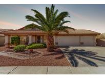 Charming home featuring a well-manicured lawn, mature palm tree, and a spacious three-car garage and a tile roof at 10937 N Ventana W Dr, Peoria, AZ 85373