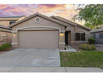 Charming single-story home with a two-car garage, desert landscaping, and a beautiful sunset sky at 13723 W Rovey Ave, Litchfield Park, AZ 85340