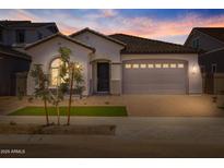Charming single-story home featuring a manicured front yard and a two-car garage at dusk at 15642 W Georgia Dr, Surprise, AZ 85379