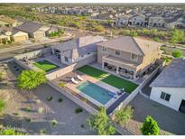 A bird's eye view of a property's backyard including a pool with lounge chairs, a barbeque, and a grassy area at 18381 W La Senda Dr, Surprise, AZ 85387