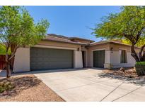 Beige home featuring an attached three-car garage with green doors and a paved driveway at 8647 W Lariat Ln, Peoria, AZ 85383
