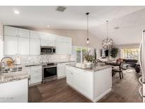 Modern kitchen with white cabinetry, granite countertops, stainless steel appliances and wood flooring at 13533 N 91St Way, Scottsdale, AZ 85260