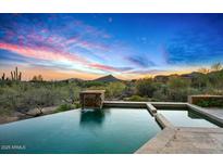 Inviting pool with a waterfall feature and scenic mountain views under a colorful sky at sunset at 39810 N 105Th Way # 128, Scottsdale, AZ 85262