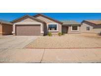 Tan single-story home features a two car garage and low maintenance gravel yard at 4542 N 86Th Dr, Phoenix, AZ 85037