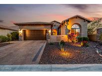Inviting desert home featuring a paver driveway, two-car garage, and mature landscaping under a colorful dusk sky at 9059 E Leonora St. St, Mesa, AZ 85207