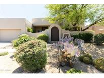 Charming home with desert landscaping, mature trees, cacti, and a decorative front gate entry at 10795 E Sutherland Way, Scottsdale, AZ 85262