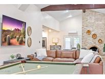Open living room featuring vaulted ceilings, a brick fireplace, leather seating, and a billiard table at 16436 N 64Th Pl, Scottsdale, AZ 85254