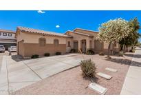 Single-story home showcasing desert landscaping, light beige stucco, and a tile roof under a bright blue sky at 2635 E Riviera Dr, Chandler, AZ 85249