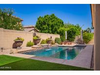 Beautiful backyard pool area with a small waterfall feature, lush greenery, and a relaxing patio space at 800 W Sycamore Ct, Litchfield Park, AZ 85340