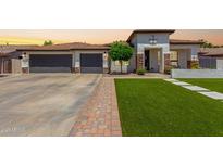 Charming single-story home featuring a well-manicured lawn, three-car garage, and neutral-toned facade with decorative stone accents at 4706 E Des Moines St, Mesa, AZ 85205