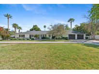 Charming single-story home featuring a spacious lawn, mature palm trees, and a three-car garage at 5339 E Osborn Rd, Phoenix, AZ 85018