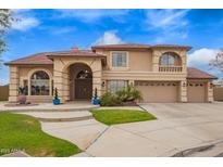 Beautiful home exterior featuring a well-maintained lawn, mature landscaping, and a spacious driveway leading to a three-car garage at 5510 N 132Nd Dr, Litchfield Park, AZ 85340