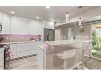 This updated kitchen features modern white cabinets, stainless steel appliances, and a breakfast bar with seating at 5913 E Thomas Rd, Scottsdale, AZ 85251