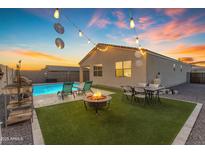 Inviting backyard oasis featuring a sparkling pool, cozy fire pit, and outdoor seating under festive string lights at 7145 E Eagle Nest Way, San Tan Valley, AZ 85143