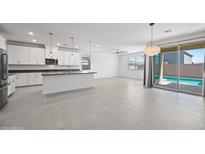 Open-concept living area with a modern kitchen, stylish pendant lighting, and a sliding glass door at 14413 W Eugene Ter, Surprise, AZ 85379
