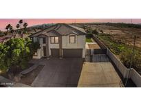 Two-story home with a tile roof, desert landscaping, an enclosed backyard, and an expansive driveway at 23214 N 106Th Ave, Peoria, AZ 85383