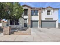 Two-story home with stone accents, neutral paint, and a spacious driveway with gray garage doors at 23214 N 106Th Ave, Peoria, AZ 85383
