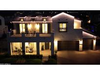 Striking two-story home exterior featuring well-manicured lawn and a welcoming facade lit with decorative lights at 3669 E Boot Track Trl, Gilbert, AZ 85296
