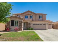 Charming two-story home with a three car garage, landscaped front yard, and beautiful desert flowers at 18419 W Maui Ln, Surprise, AZ 85388