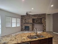 Inviting living room with a brick fireplace, granite countertops, and plenty of natural light at 18447 W Verdin Rd, Goodyear, AZ 85338