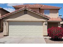 Tan two-story home featuring a two-car garage and vibrant red bougainvillea bush at 22320 W Morning Glory St, Buckeye, AZ 85326