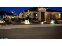 Stunning single-story home with beautiful desert landscaping and modern lighting at night at 27021 W Kerry Ln, Buckeye, AZ 85396