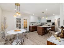 Bright kitchen features modern white cabinets, wood accents, stainless appliances, and a dining area with unique lighting at 6957 E Osborn Rd # A, Scottsdale, AZ 85251