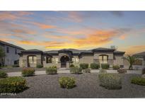 Beautiful single-story home with manicured landscaping and a stone-accented facade under a dramatic sunset sky at 8024 W Vista Ave, Glendale, AZ 85303