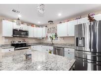 Modern kitchen featuring stainless steel appliances and granite countertops, with white cabinets and an island at 930 E Friar Ave, Apache Junction, AZ 85119