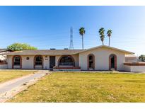 Charming single-story home featuring a lush lawn, arched windows, and inviting curb appeal at 1829 E Decatur St, Mesa, AZ 85203