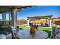 Outdoor living space boasts an extended covered patio, artificial turf, and a well-maintained landscape at 27636 W Runion Dr, Buckeye, AZ 85396