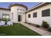Stunning home featuring a well-manicured lawn, stylish outdoor seating, and a unique rounded architectural design at 7614 E Cactus Wren Rd, Scottsdale, AZ 85250