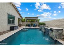 A refreshing pool offers beautiful waterfalls and a pergola with seating, creating a perfect backyard oasis at 9834 E Thatcher Ave, Mesa, AZ 85212