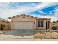 Tan single-story home featuring a two-car garage, desert landscaping, and an arched entryway at 15134 N 138Th Ln, Surprise, AZ 85379