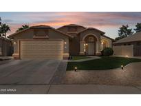 Charming single-story home with a two-car garage, well-manicured lawn, and desert landscaping at sunset at 2236 E Rawhide St, Gilbert, AZ 85296