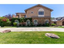 Beautiful two-story home with a stone facade, lush landscaping, and arched windows at 3203 E Ellis St, Mesa, AZ 85213