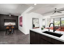 Modern kitchen with sleek, dark cabinetry, white countertops, a breakfast bar and stainless steel appliances at 7167 E Rancho Vista Dr # 4010, Scottsdale, AZ 85251