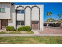 Charming townhouse featuring unique arched brickwork and a well-maintained front lawn at 7647 E Montecito Ave, Scottsdale, AZ 85251