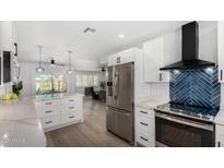 Bright, open kitchen features stainless steel appliances, white cabinets, and a modern backsplash at 855 S Revolta Cir, Mesa, AZ 85208