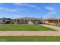 Charming brick home features a well-manicured lawn, classic white trim, and an attached carport for convenient parking at 1944 W Osborn Rd, Phoenix, AZ 85015