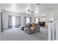 Spacious carpeted living room featuring a sectional couch and an open layout to the dining area at 44175 W Knauss Dr, Maricopa, AZ 85138